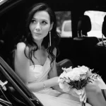 Bride stepping out of a white wedding limo in Houston with groom waiting outside