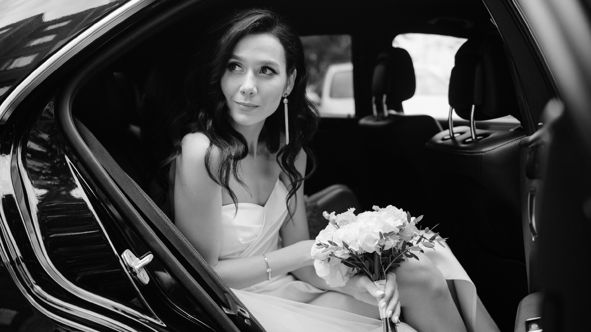 Bride stepping out of a white wedding limo in Houston with groom waiting outside